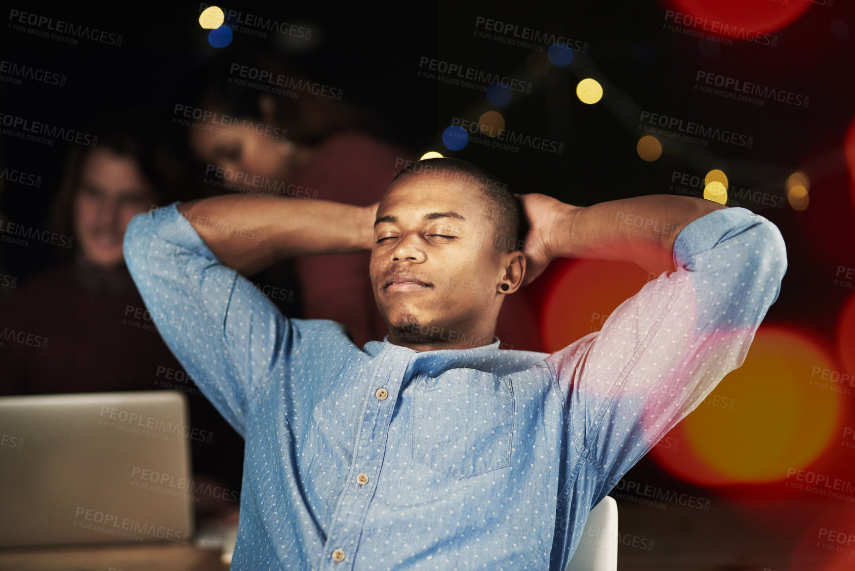 Buy stock photo Shot of a handsome young man looking relaxed while working late in the office