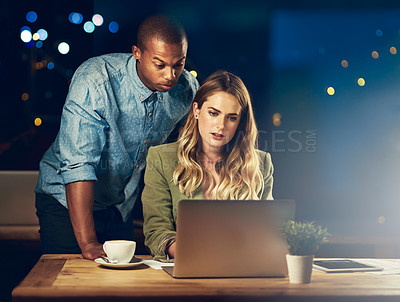 Buy stock photo Shot of two young colleagues working late in the office together