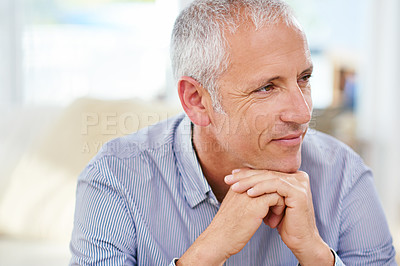 Buy stock photo Shot of a mature man sitting on his sofa deep in thought
