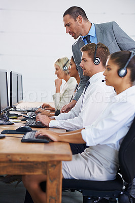 Buy stock photo Help desk, manager and phone call with team typing on computer, consultation and customer support. Headset, telemarketing and client service agent at callcenter with training in coworking space	