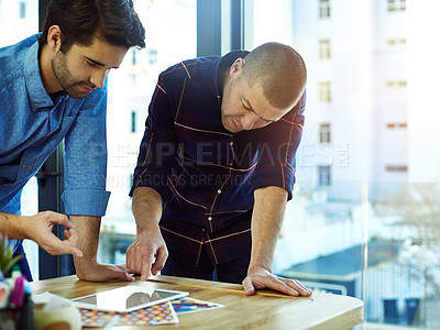 Buy stock photo Cropped shot of two coworkers discussing something on a digital tablet