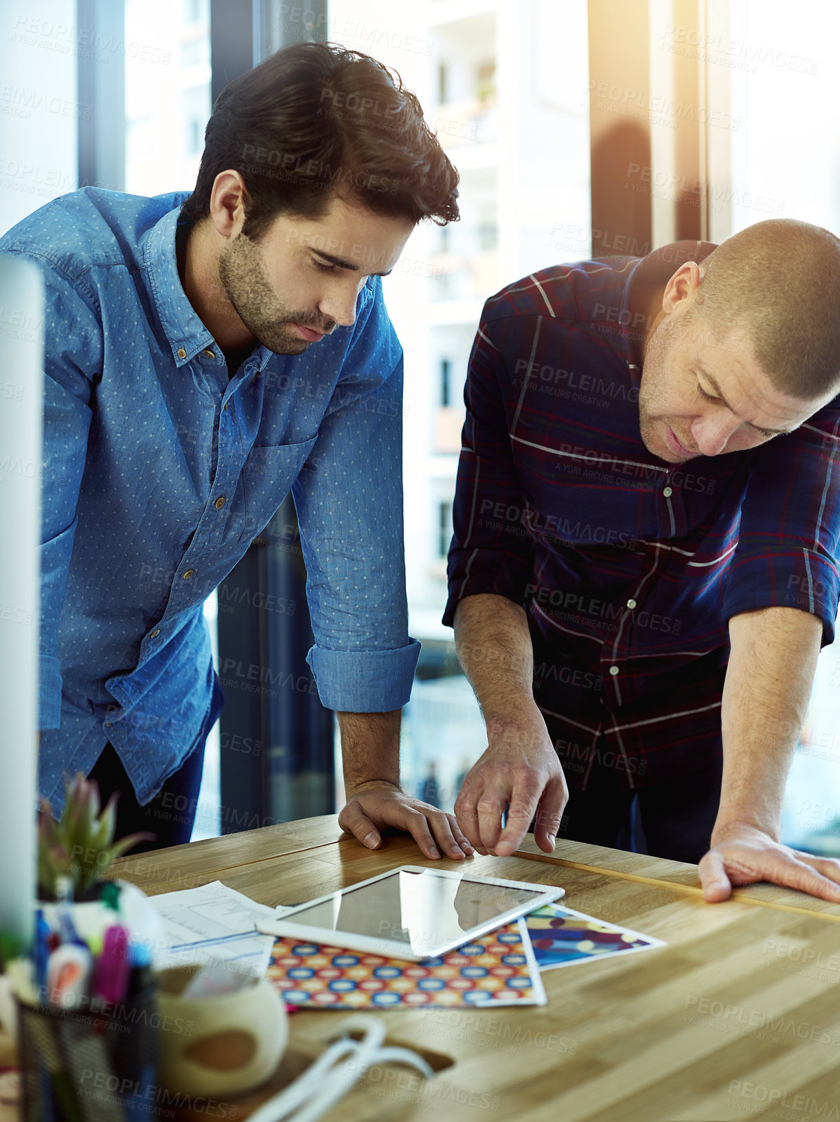 Buy stock photo Cropped shot of two coworkers discussing something on a digital tablet