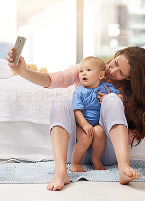 Buy stock photo Shot of a mother and her baby boy taking a selfie together at home