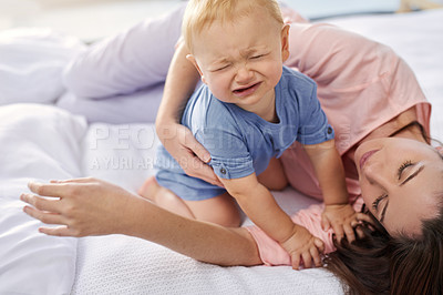 Buy stock photo Cropped shot of a mother lying down with her crying baby boy at home