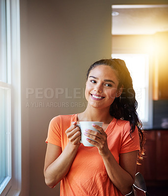 Buy stock photo Shot of a smiling young woman lstanding by a window while drinking a coffee at home