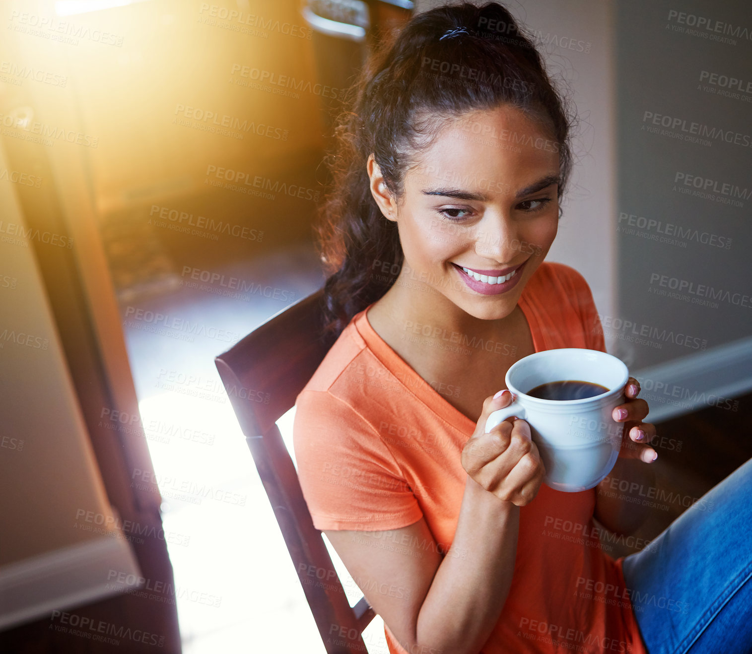 Buy stock photo Shot of a smiling young woman drinking coffee while sitting in a chair at home