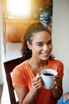 Buy stock photo Portrait of a smiling young woman drinking coffee while sitting in a chair at home