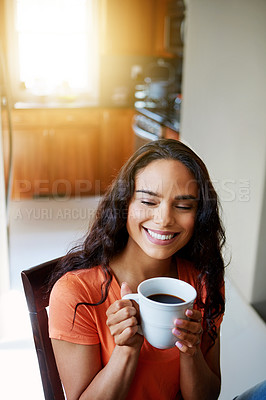 Buy stock photo Shot of a smiling young woman drinking coffee while sitting in a chair at home