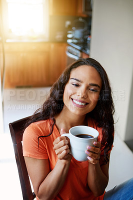 Buy stock photo Shot of a smiling young woman drinking coffee while sitting in a chair at home