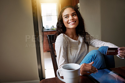 Buy stock photo Shot of a young woman drinking coffee and shopping online with her digital tablet at home