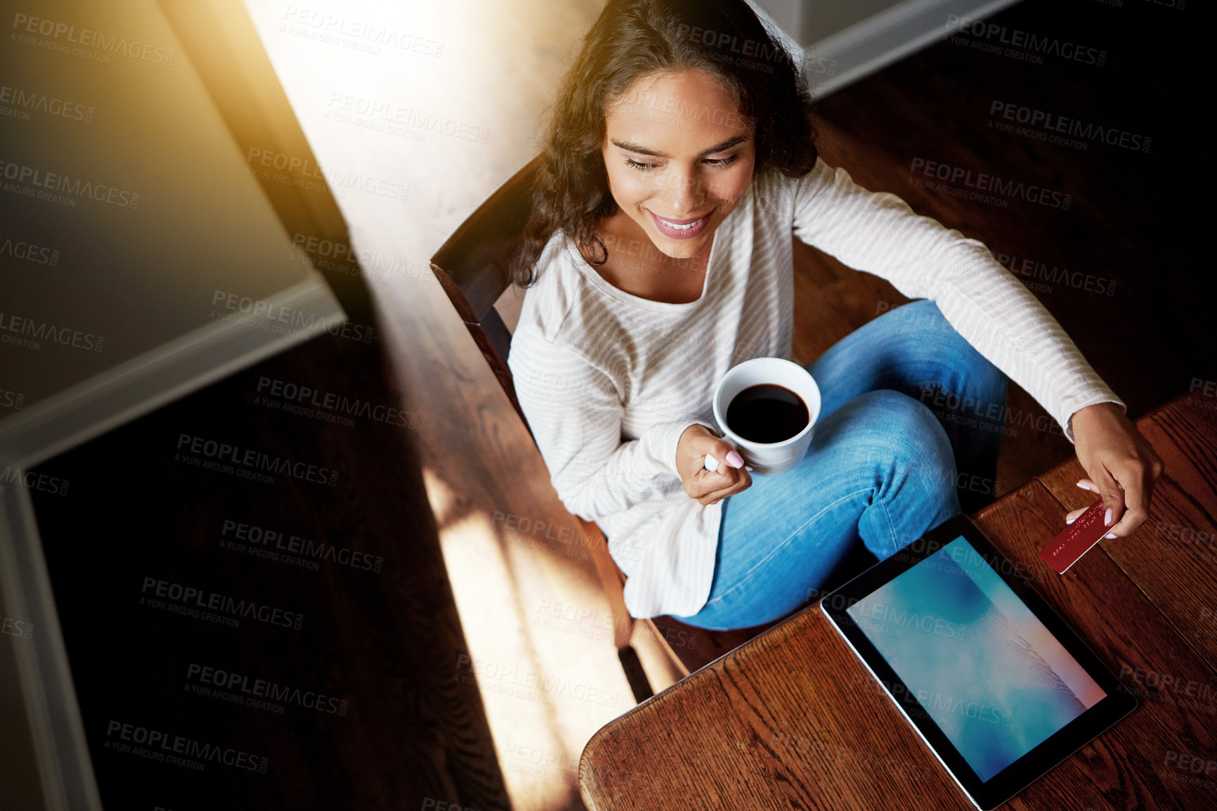 Buy stock photo High angle shot of a young woman drinking coffee and shopping online with her digital tablet at home