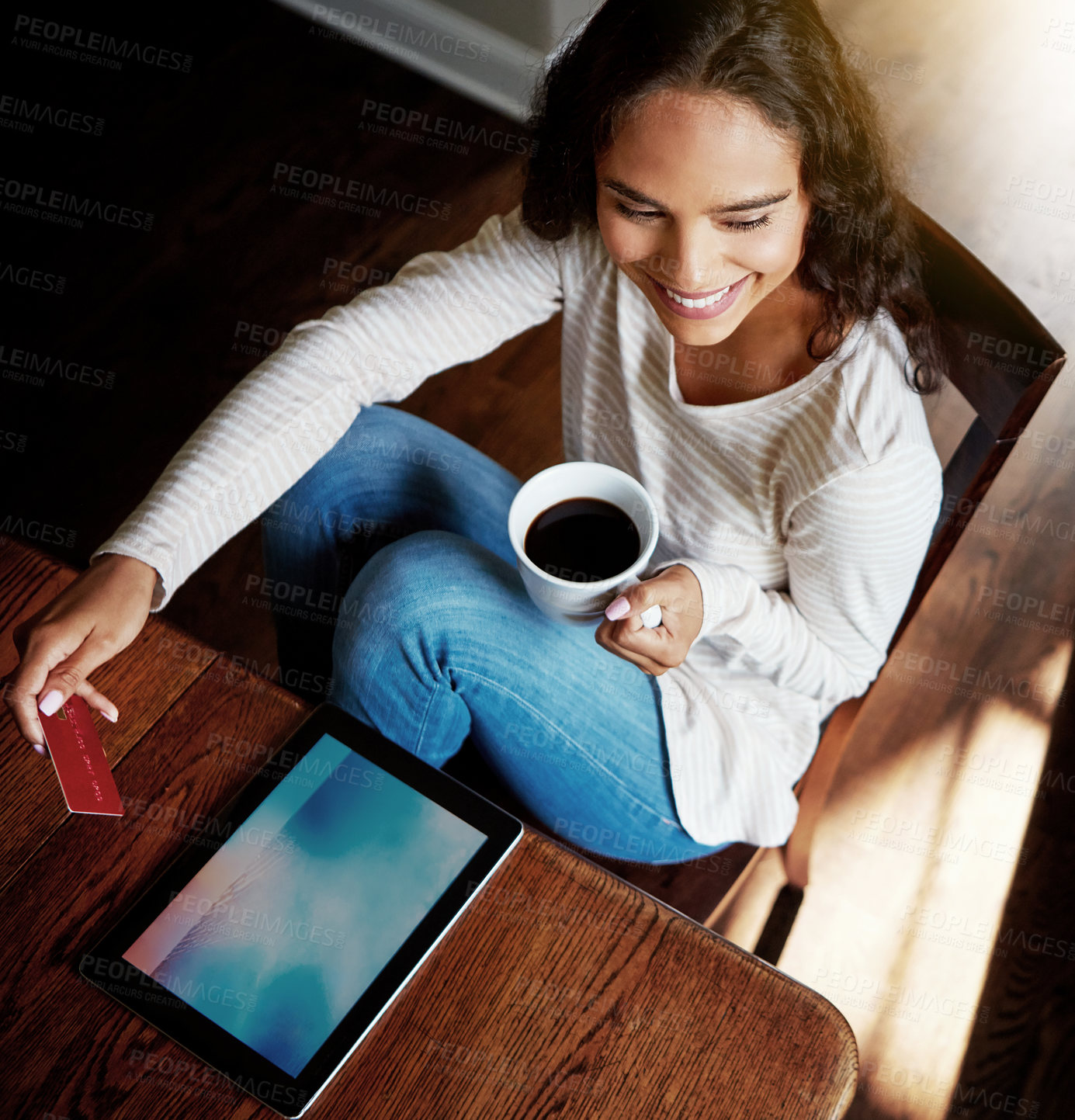 Buy stock photo High angle shot of a young woman drinking coffee and shopping online with her digital tablet at home