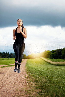 Buy stock photo Shot of a fit young woman out for a run on a beautiful day