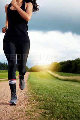 Buy stock photo Shot of an unidentifiable young woman out for a run on a beautiful day