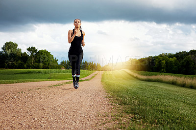 Buy stock photo Shot of a fit young woman out for a run on a beautiful day