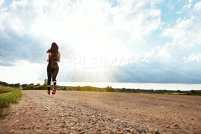 Buy stock photo Rearview shot of a young woman out for a run on a beautiful day