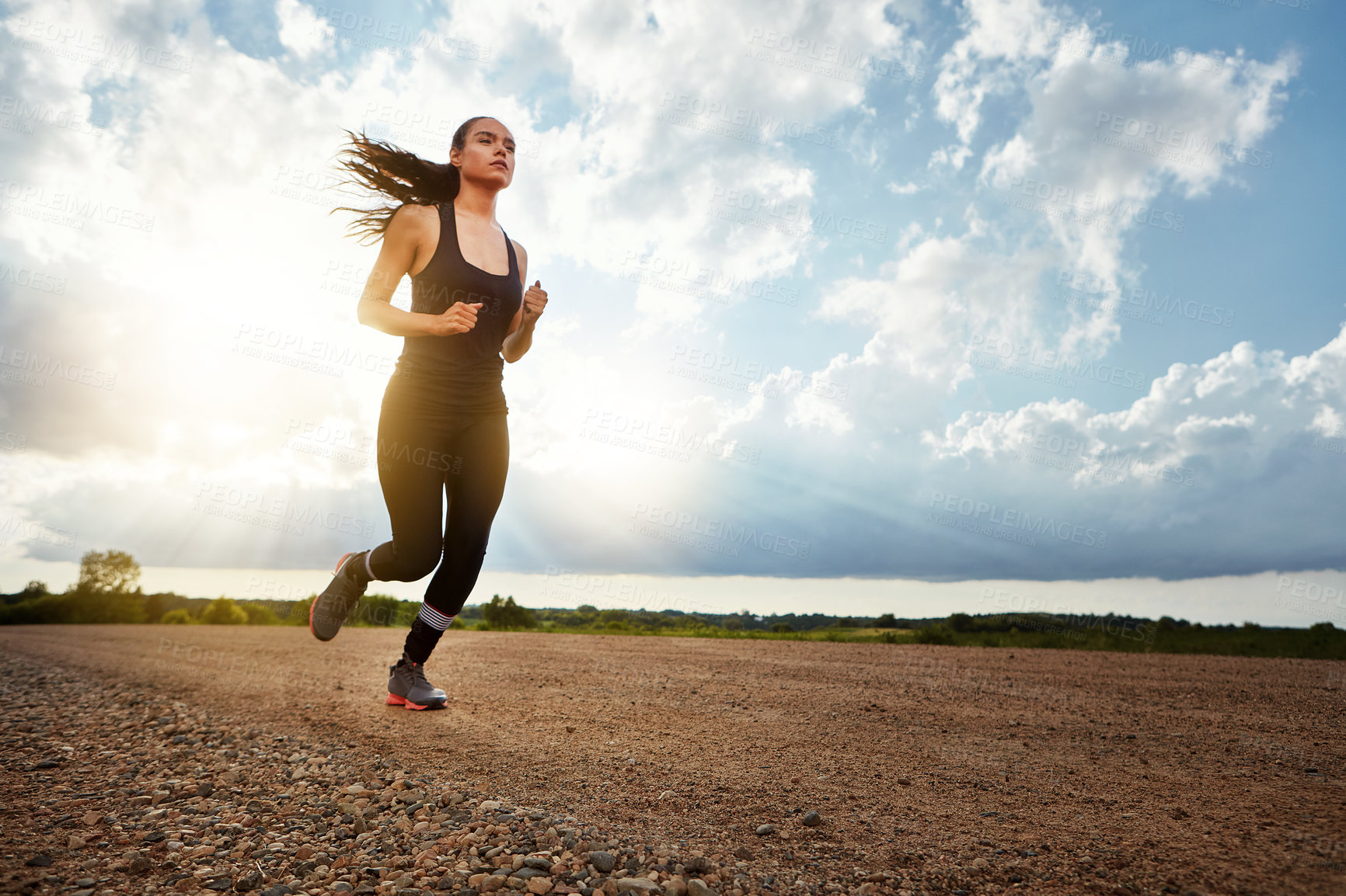 Buy stock photo Shot of a fit young woman out for a run on a beautiful day