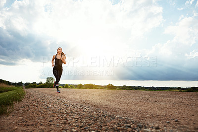 Buy stock photo Shot of a fit young woman out for a run on a beautiful day