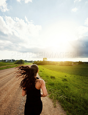 Buy stock photo Rearview shot of a young woman out for a run on a beautiful day