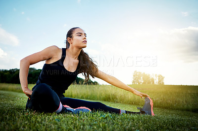 Buy stock photo Shot of a fit young woman stretching before going for a run outside on a beautiful day