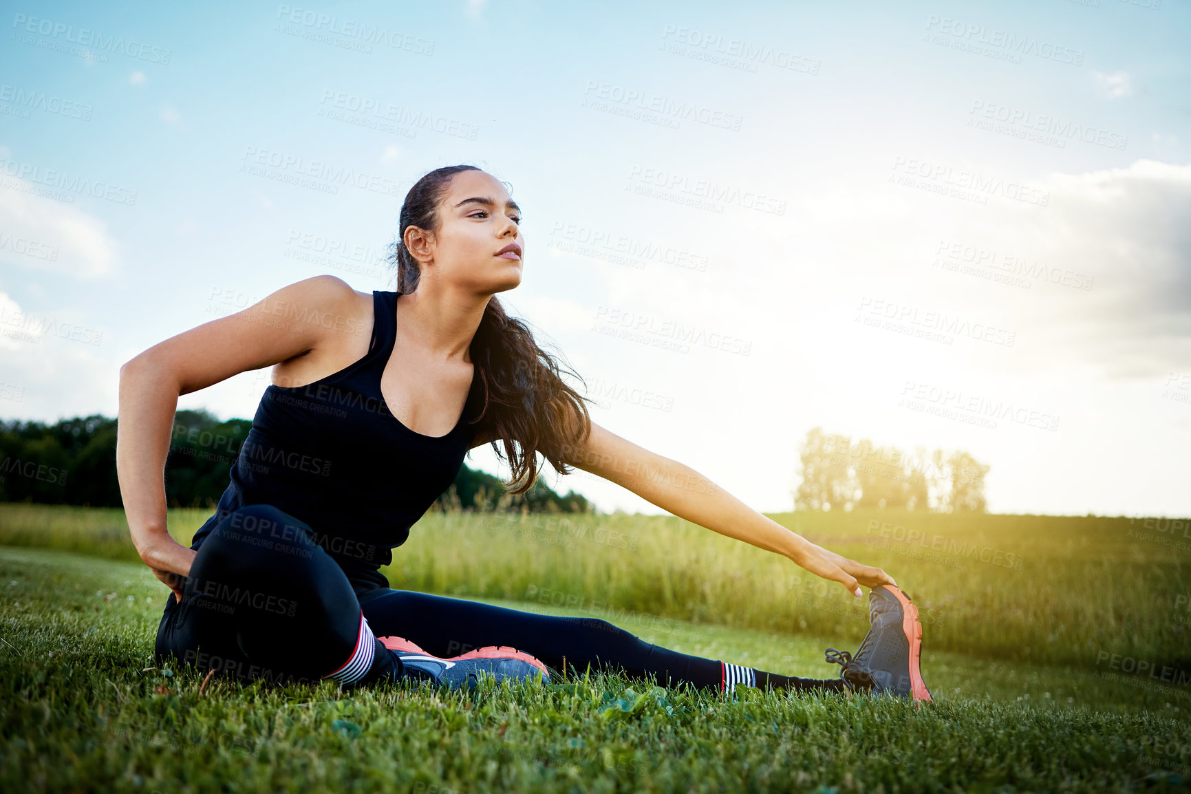 Buy stock photo Shot of a fit young woman stretching before going for a run outside on a beautiful day