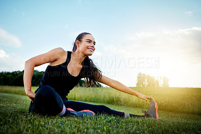 Buy stock photo Shot of a fit young woman stretching before going for a run outside on a beautiful day