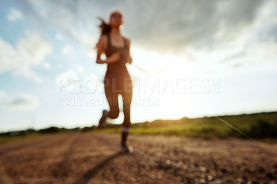 Buy stock photo Shot of a fit young woman out for a run on a beautiful day