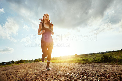 Buy stock photo Shot of a fit young woman out for a run on a beautiful day