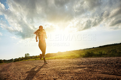 Buy stock photo Shot of a fit young woman out for a run on a beautiful day