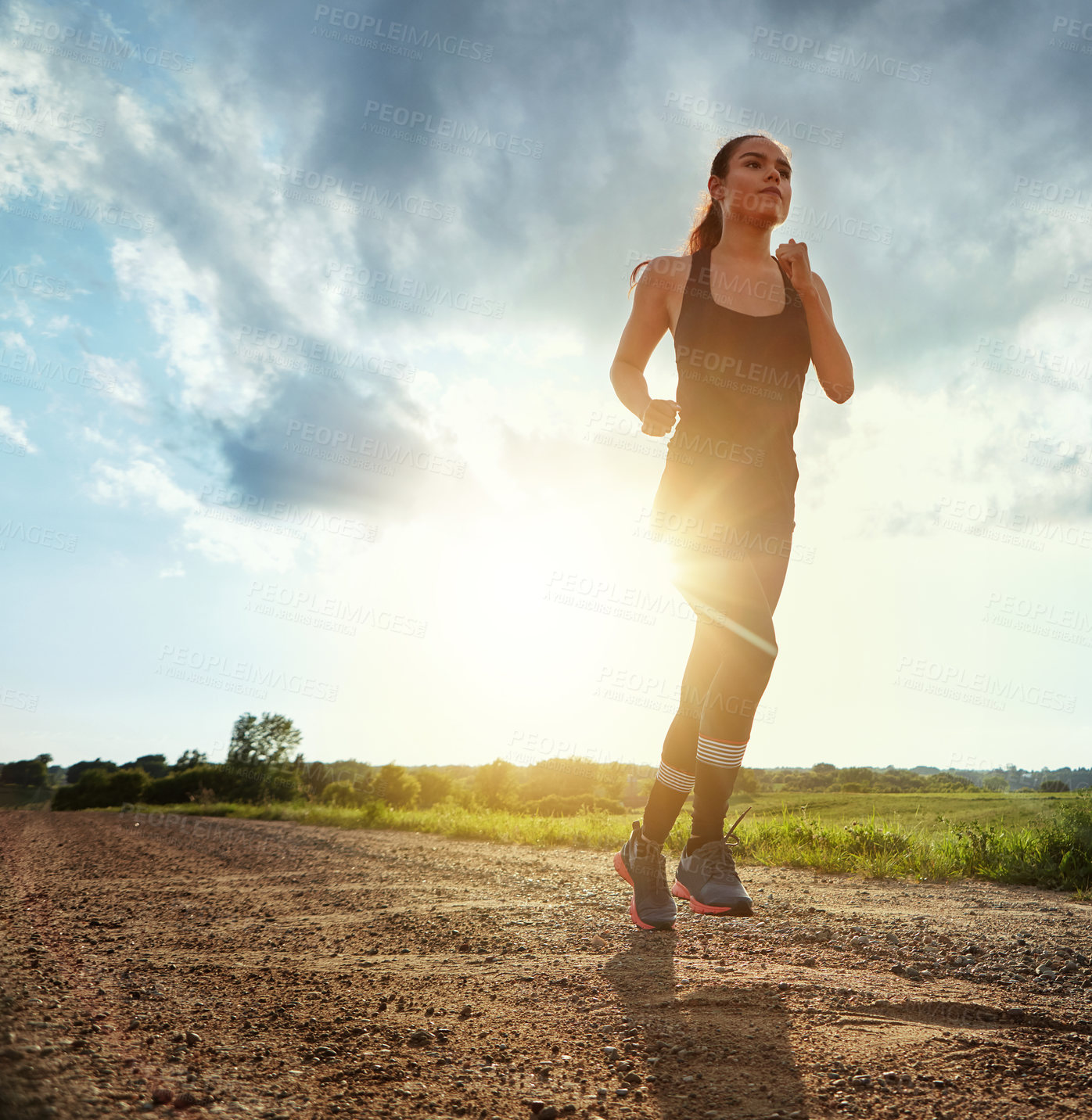 Buy stock photo Shot of a fit young woman out for a run on a beautiful day