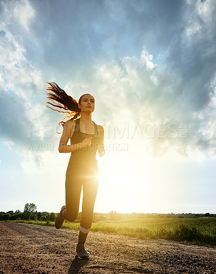 Buy stock photo Shot of a fit young woman out for a run on a beautiful day