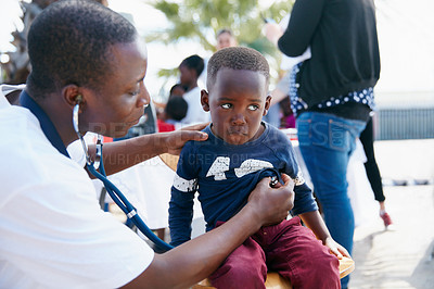 Buy stock photo Shot of a volunteer doctor giving checkups to underprivileged kids