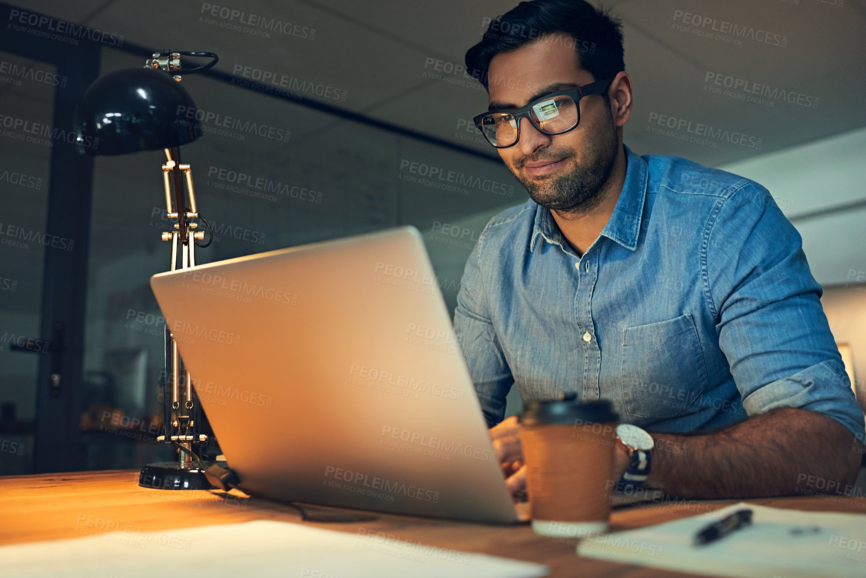 Buy stock photo Cropped shot of a young businessman working late on a laptop in an office
