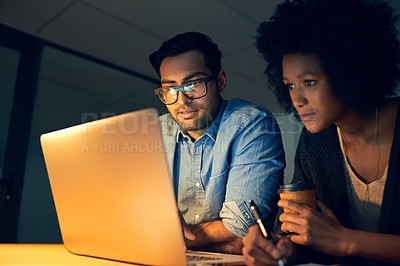 Buy stock photo Cropped shot of two colleagues working late on a laptop in an office