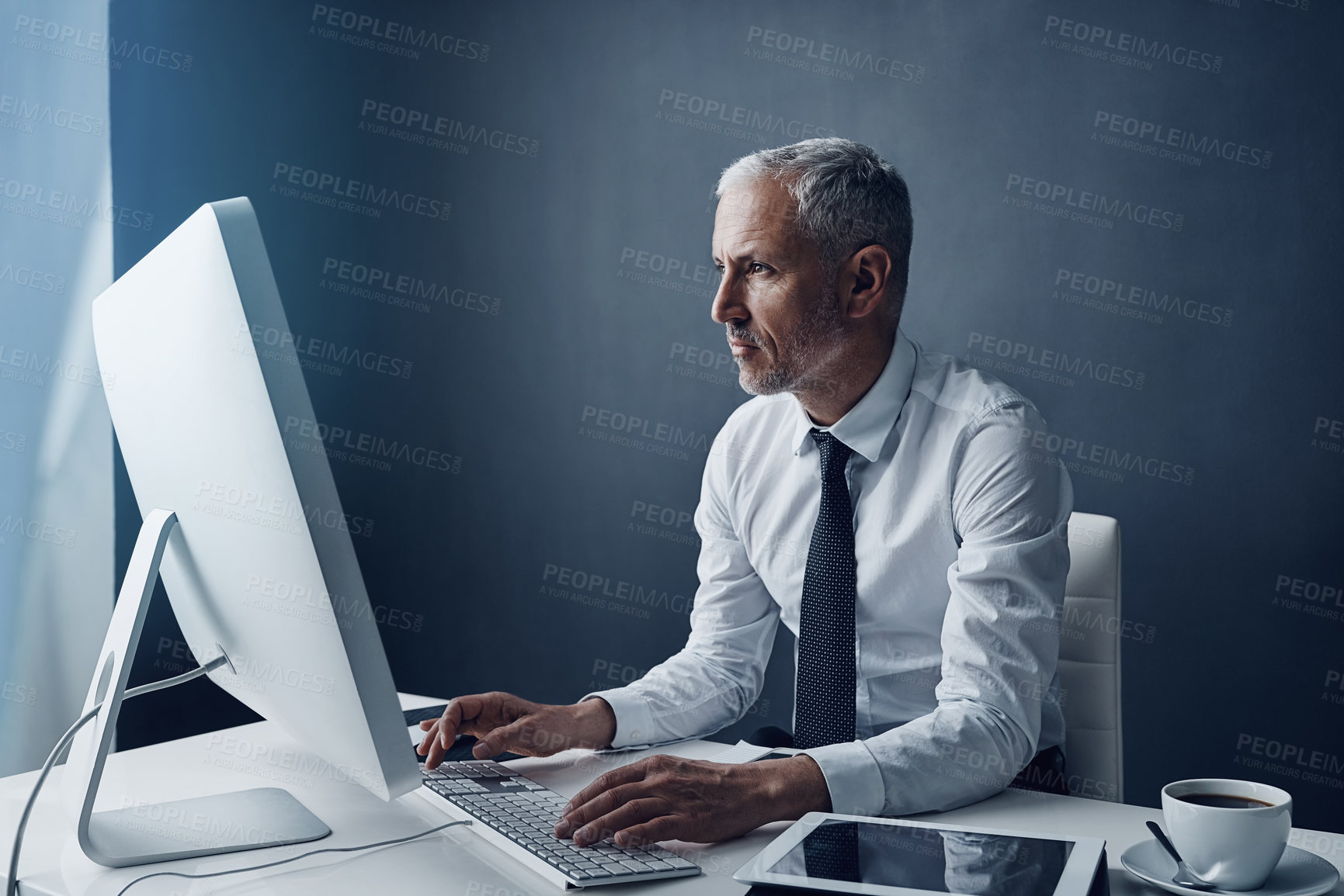 Buy stock photo Typing accountant, computer and elderly man in studio, working and isolated on a dark background mockup. Focus, writing or serious executive at desktop for reading email, research or business auditor