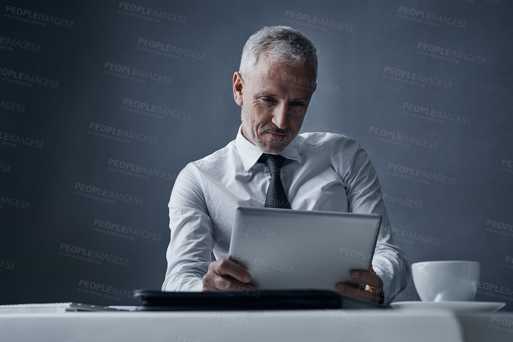 Buy stock photo Tablet, accountant and mature business man in studio isolated on a dark background mockup space. Technology, reading and senior manager at desk for working on project, audit email or research app.
