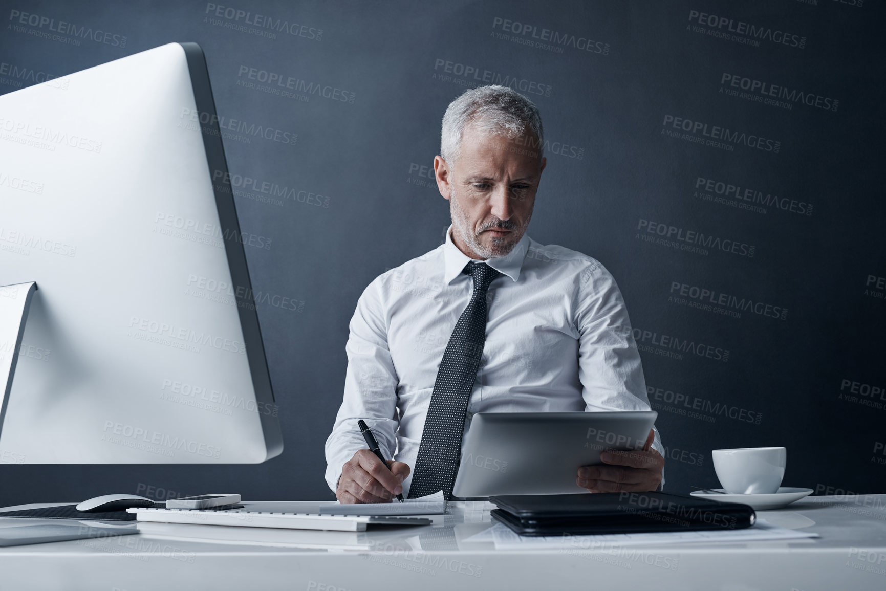 Buy stock photo Tablet, accountant and senior man writing in studio isolated on a dark background mockup space. Technology, notes and serious manager at desk to work on audit project, reading email or business app.