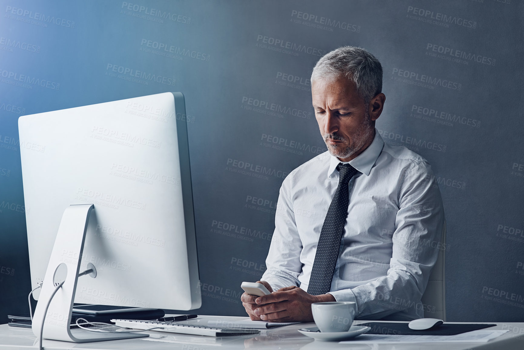 Buy stock photo Technology, mature businessman with smartphone and against studio background with computer at desk. Online communication or social networking, connectivity and male person typing email on cellphone