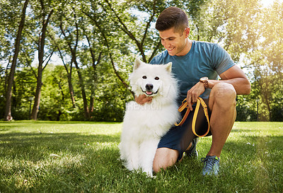 Buy stock photo Shot of a handsome young man walking his dog in the park