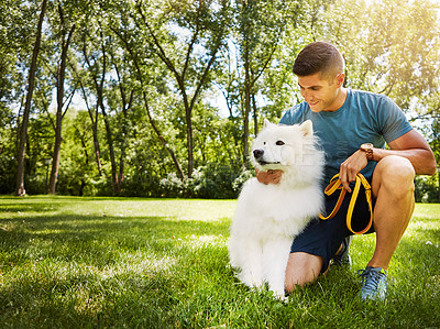 Buy stock photo Shot of a handsome young man walking his dog in the park