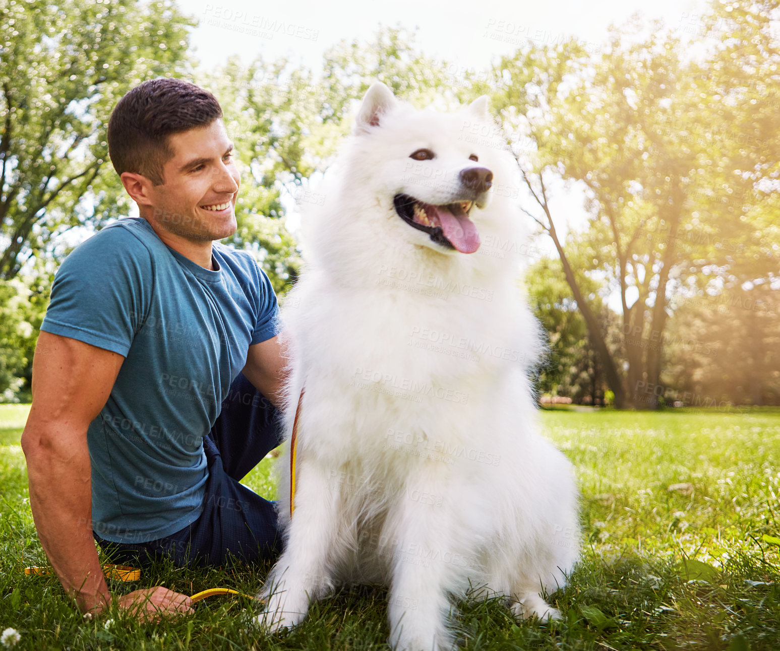 Buy stock photo Shot of a handsome young man walking his dog in the park