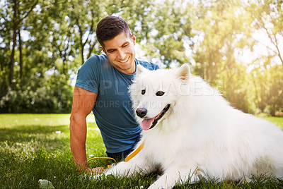 Buy stock photo Shot of a handsome young man walking his dog in the park