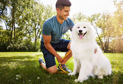 Buy stock photo Shot of a handsome young man walking his dog in the park