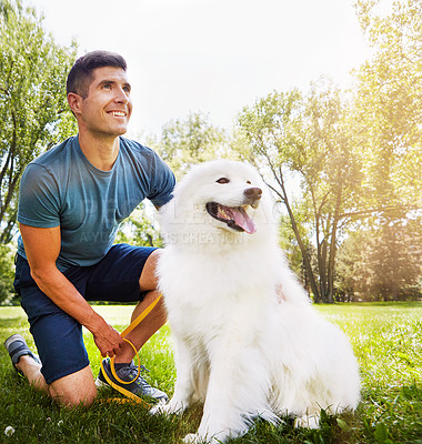 Buy stock photo Shot of a handsome young man walking his dog in the park