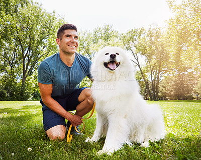 Buy stock photo Shot of a handsome young man walking his dog in the park