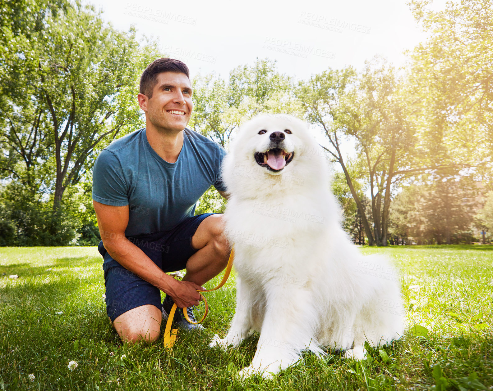 Buy stock photo Shot of a handsome young man walking his dog in the park