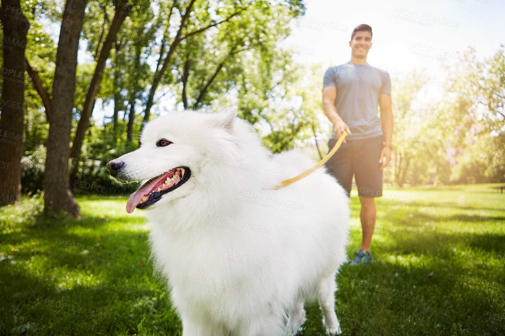 Buy stock photo Shot of a handsome young man walking his dog in the park