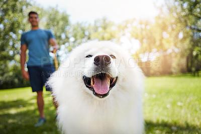 Buy stock photo Shot of a handsome young man walking his dog in the park