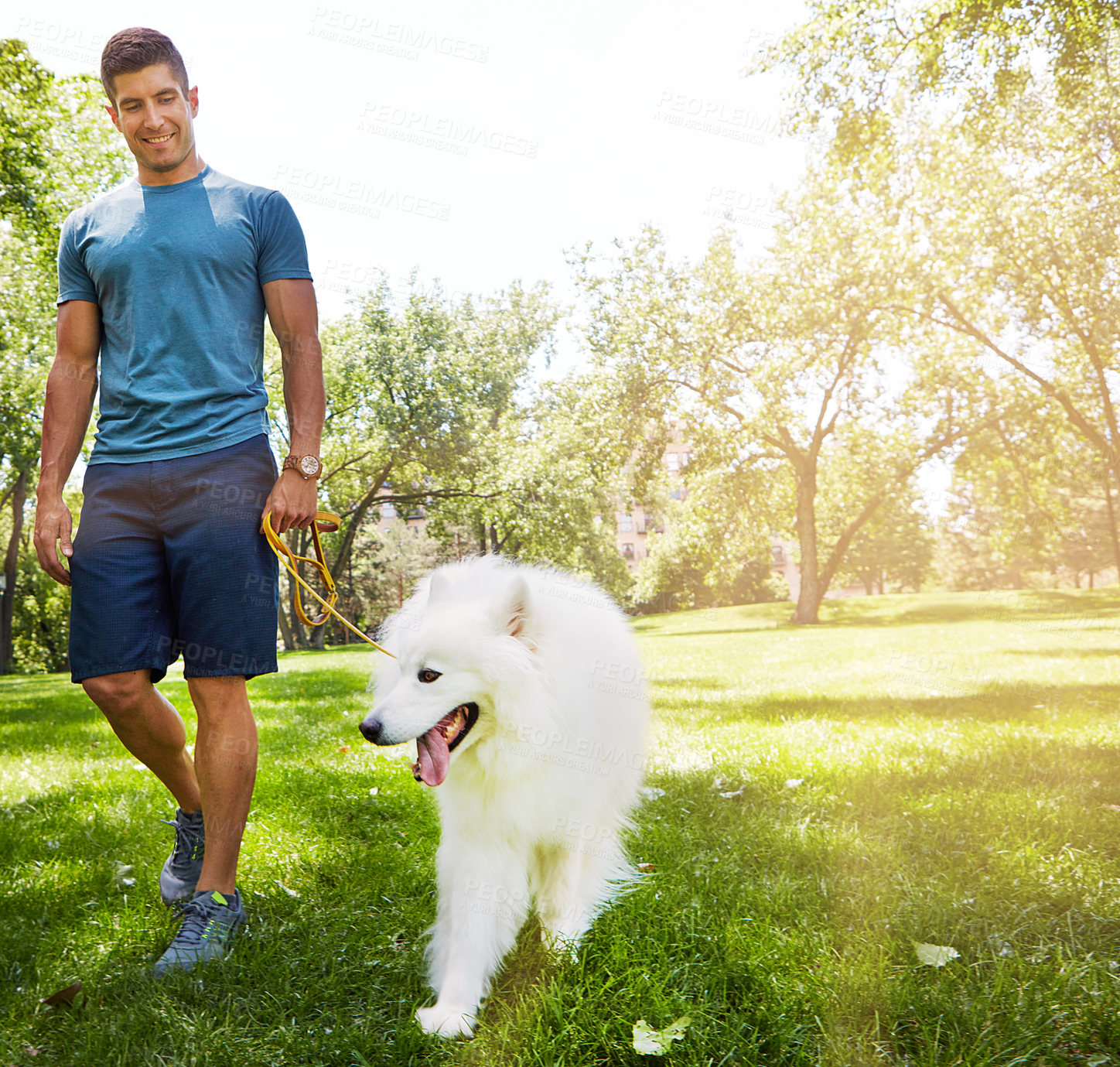 Buy stock photo Shot of a handsome young man walking his dog in the park