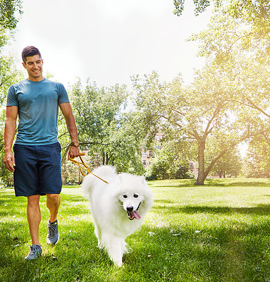 Buy stock photo Shot of a handsome young man walking his dog in the park